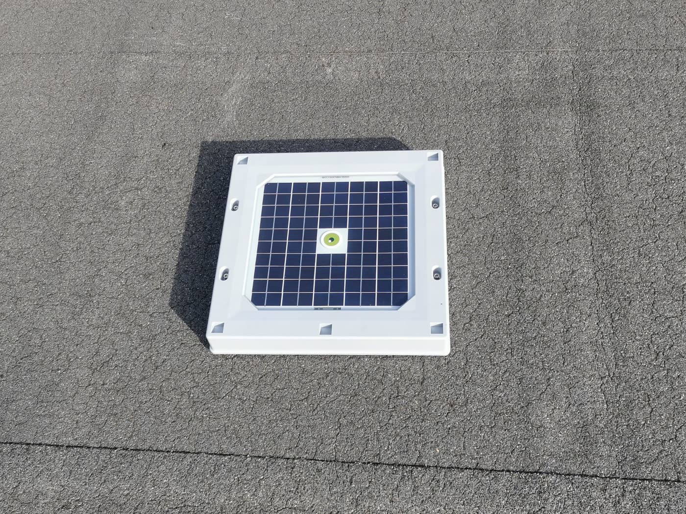 A Hailios Tessera HAIL sensor seated on a flat roof membrane, its solar impact surface facing the sky